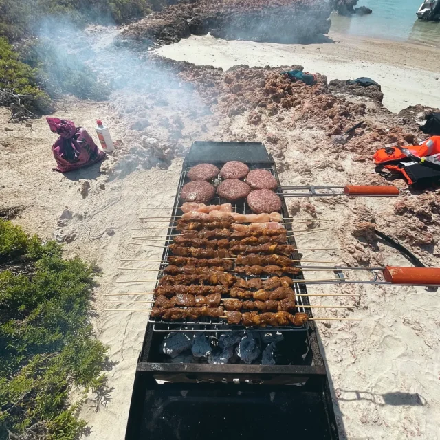 A barbecue grilling on the beach beside the camp