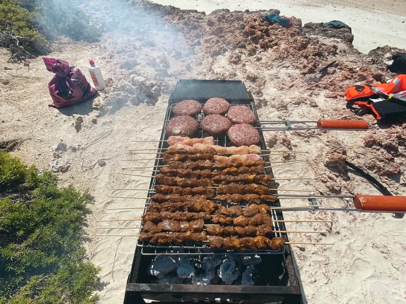 A barbecue grilling on the beach beside the camp