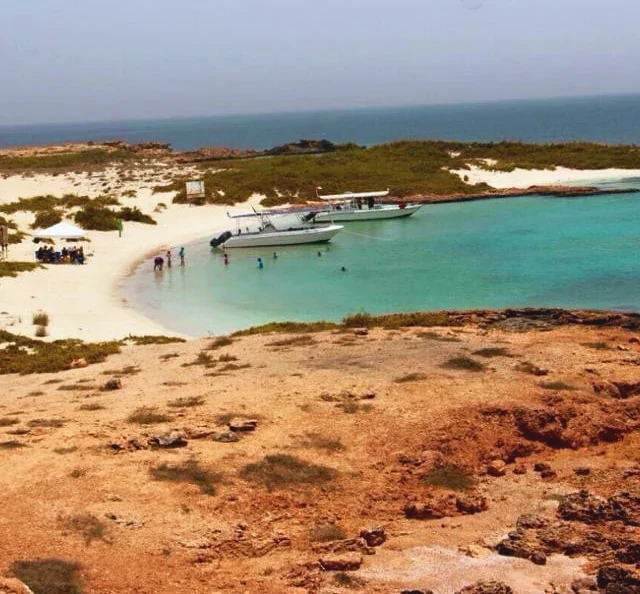 Two boats anchored in a turquoise lagoon while guests swim