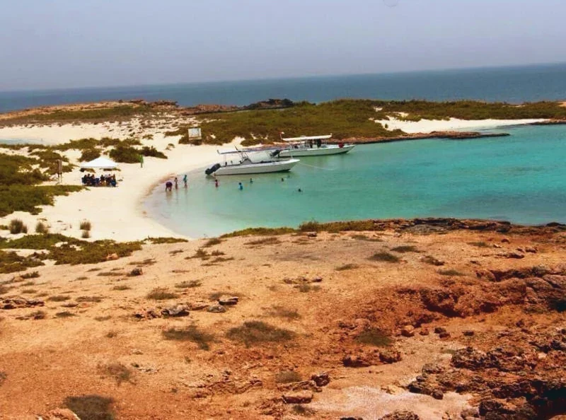 Two boats anchored in a turquoise lagoon while guests swim