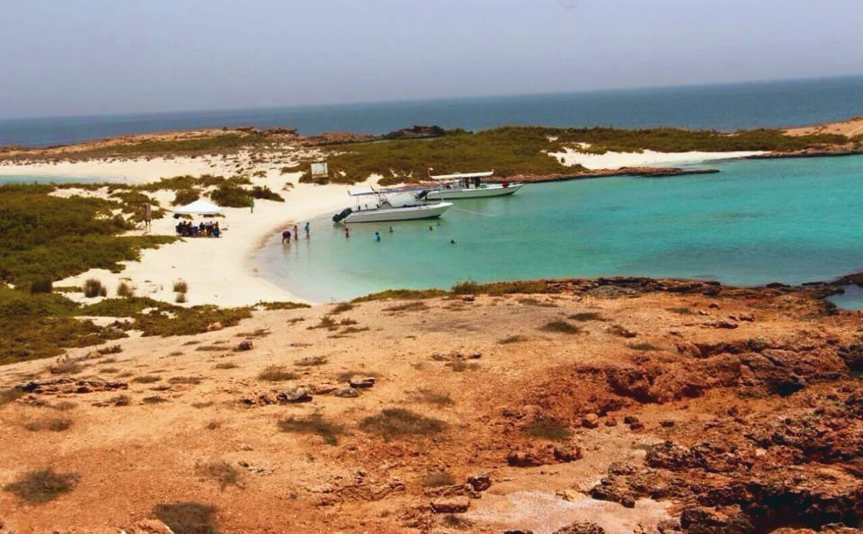 Two boats anchored in a turquoise lagoon while guests swim