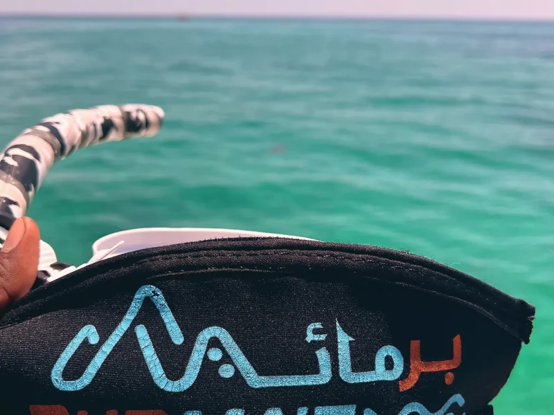 A snorkel mask with the Burmae strap over turquoise water