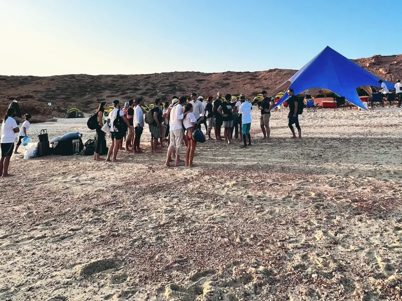 Guests gathering on the beach beside the camp canopy