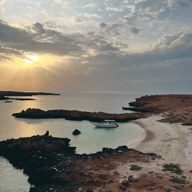 A boat anchored in a quiet cove at sunset