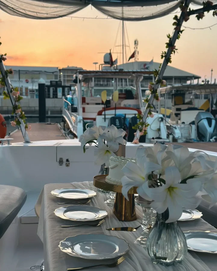 A dinner table dressed with white lilies on deck at sunset