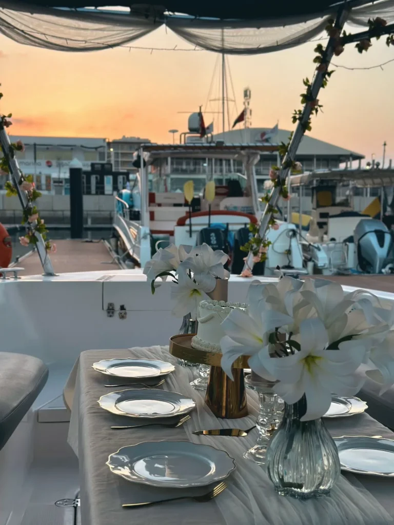 A dinner table dressed with white lilies on deck at sunset