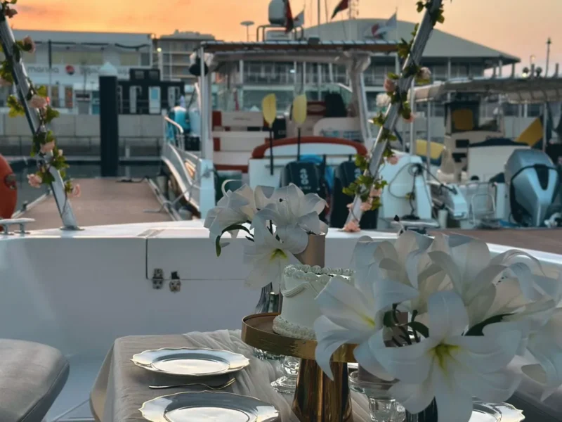 A dinner table dressed with white lilies on deck at sunset