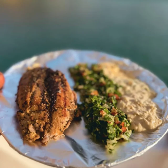 Grilled fish with tabbouleh and hummus, served by the water