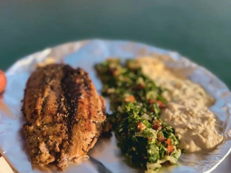Grilled fish with tabbouleh and hummus, served by the water