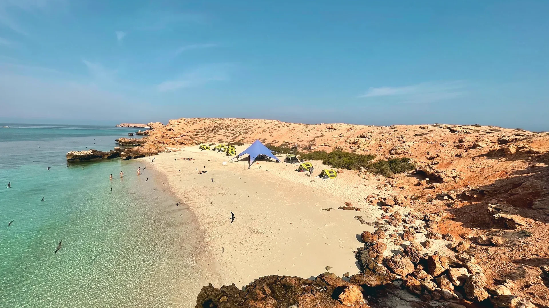 Looking down on the camp from the rocks, above clear shallow water