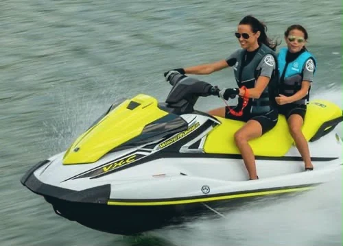 Two riders on a jet ski skimming past the camera