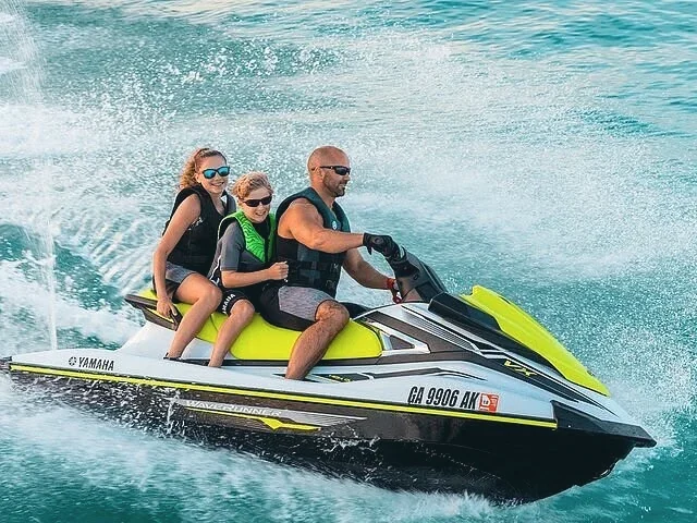 Three riders on a jet ski throwing up spray