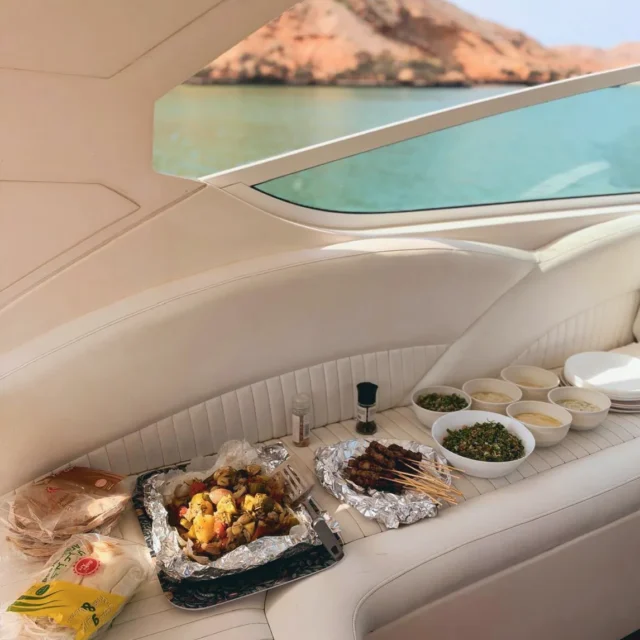 Lunch laid out on the yacht: grilled vegetables, skewers, salads and dips, a rocky bay through the window