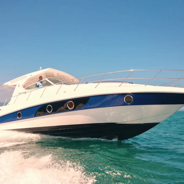 A white motor yacht with a blue hull stripe under way