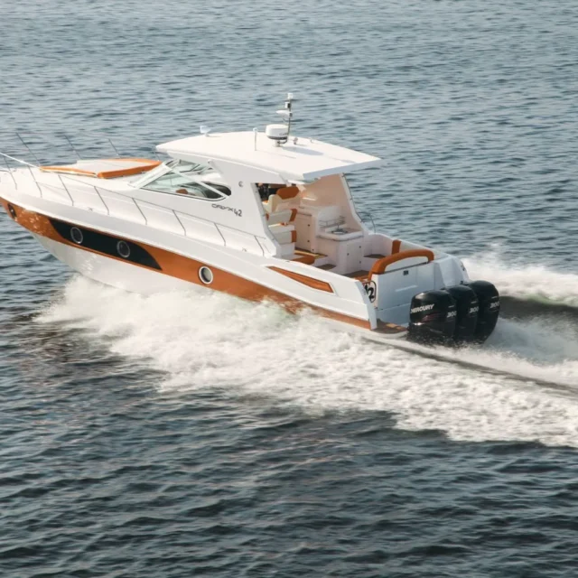A white motor yacht with an orange hull stripe under way